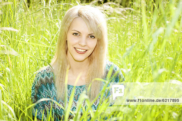 Smiling young woman sitting in long grass