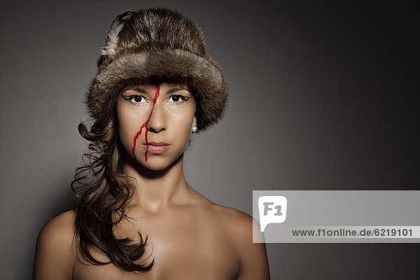 Frau mit Pelzmütze auf dem Kopf und Blut im Gesicht  Portrait