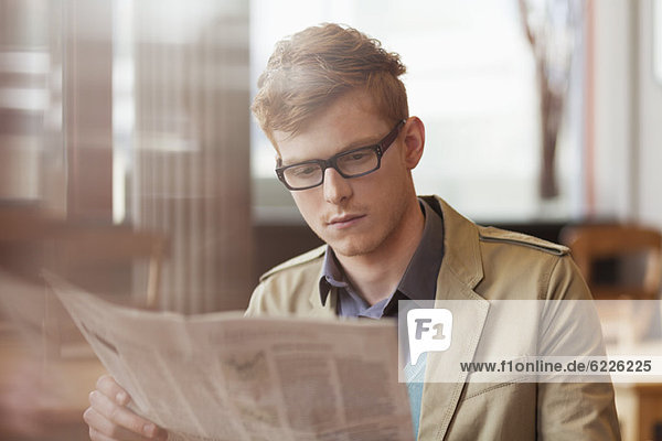 Ein Mann  der eine Zeitung in einem Restaurant liest.