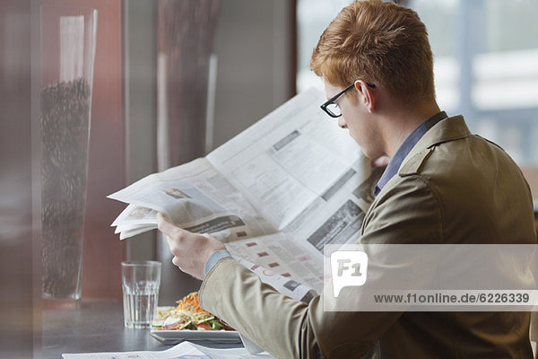 Man sitting in a restaurant and reading a newspaper