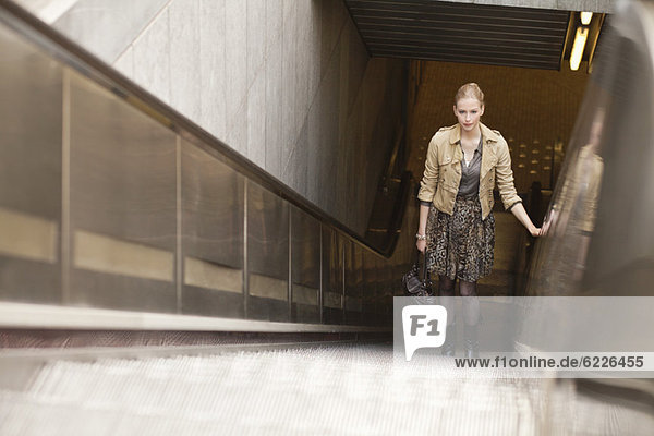 Businesswoman standing on escalator