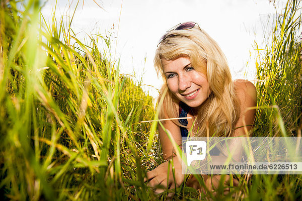 Junge Frau liegt im hohen Gras