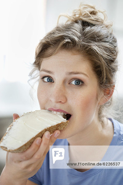Portrait of a woman eating toast with cream spread on it