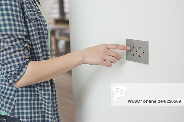 Woman pressing light switch on a wall