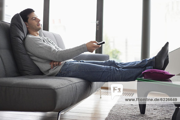 Man reclining on a couch and watching television