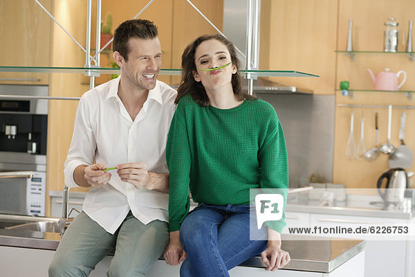 Couple playing with green bean in the kitchen