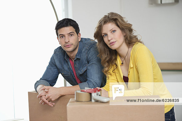 Couple leaning over cardboard boxes