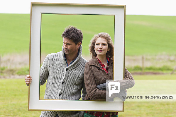 Couple holding a frame in a field