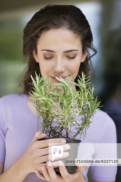 Frau riecht eine Rosmarinpflanze