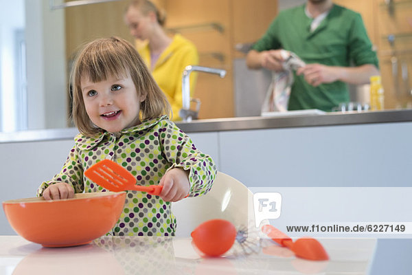 Süßes kleines Mädchen mit Schlitzlöffel und Rührschüssel in der Küche