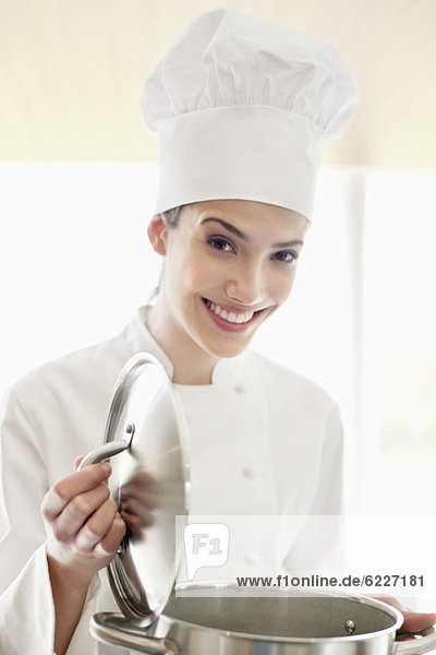 Happy female chef holding a saucepan