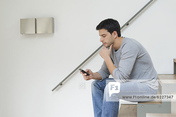Mann  der mit dem Handy auf der Treppe sitzt