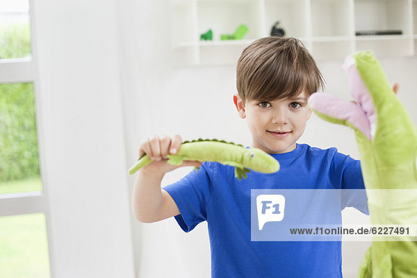 Porträt eines Jungen  der mit Tierspielzeug spielt