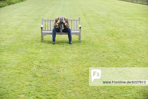Depressed man sitting on a bench in a park