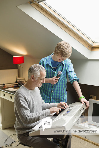 Ein Mann  der mit seinem Sohn zu Hause ein E-Piano spielt.