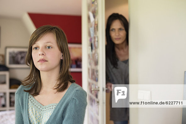 Woman watching her daughter behind the door in the bedroom