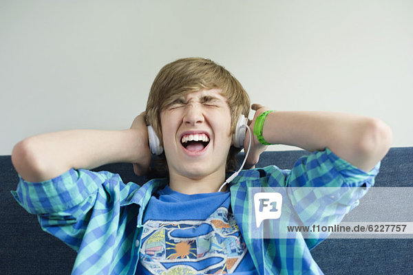 Teenager-Junge  der Musik hört und aufgeregt aussieht.