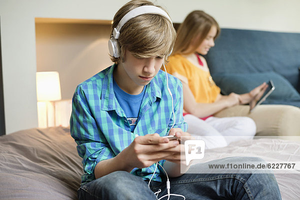 Teenager-Junge hört mit seiner Schwester Musik auf dem iPod und benutzt dabei ein digitales Tablett.