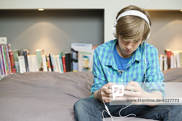 Teenager-Junge hört Musik auf dem iPod zu Hause