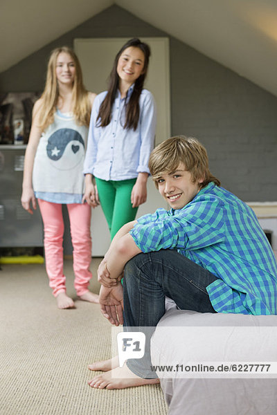 Teenager-Junge mit seinen beiden Schwestern lächelnd zu Hause