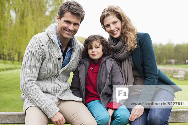 Junge sitzend mit seinen Eltern am Tor einer Hütte