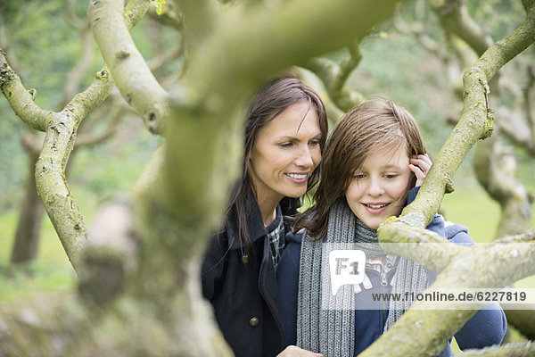 Woman with her daughter looking at a tree branch in an orchard