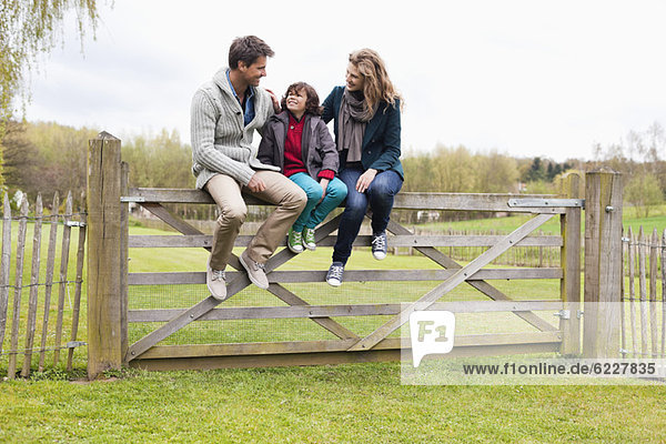 Boy sitting with his parents on the gate of a cottage