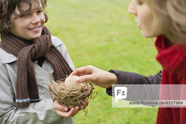 Boy showing a bird's nest to his mother