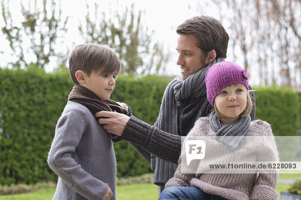 Man putting on warm clothing to his children
