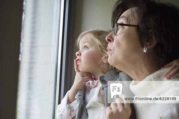 Frau mit ihrer Enkelin beim Blick durchs Fenster