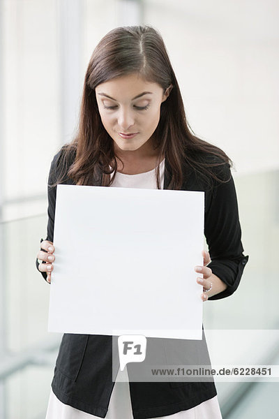Geschäftsfrau mit einem leeren Plakat in einem Büro
