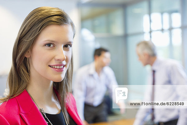 Portrait of a businesswoman smiling in an office with her colleagues discussing in the background
