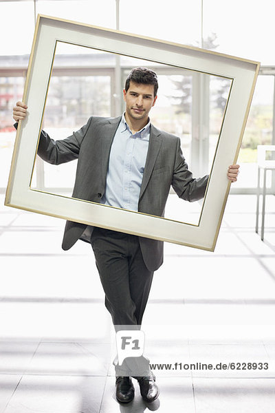Businessman holding a frame in an office lobby