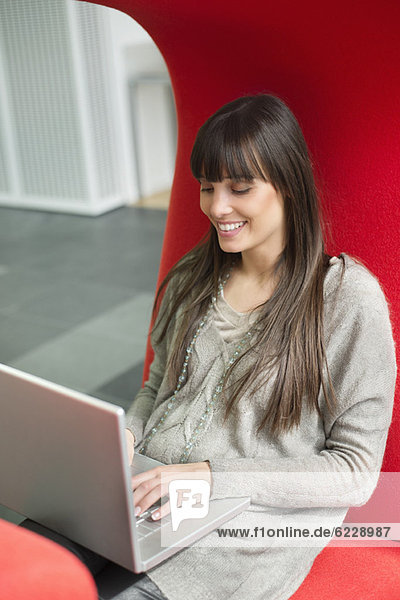 Businesswoman using a laptop and smiling in an office
