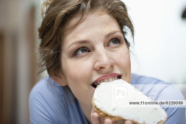 Woman eating a toast with cream spread on it