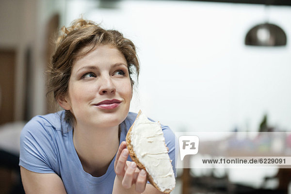 Nahaufnahme einer Frau  die Toast mit Sahneaufstrich isst.