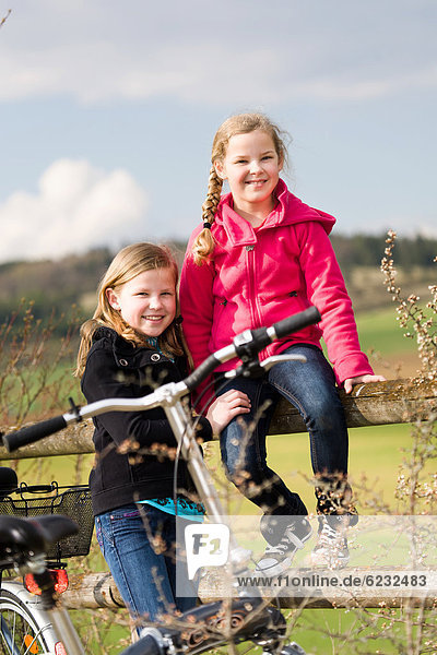 Two girls with bicycles in rural landscape