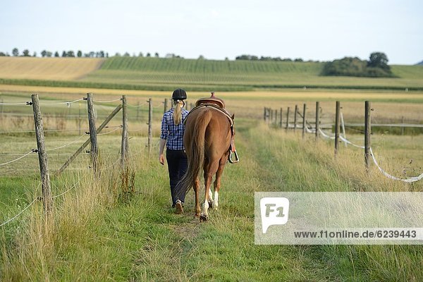 Teenagerin mit Pferd auf der Koppel