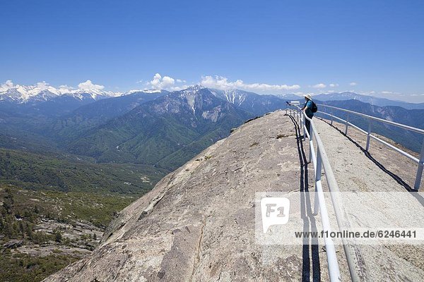 Tourist hiker  on top of Moro Rock overlooking the Sequoia foothills  looking towards Kings Canyon and the high mountains of the Sierra Nevada  Sequoia National Park  California  United States of America  North America