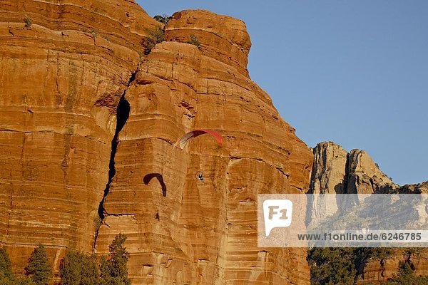 A paraglider flies past a red rock formation  Coconino 0tio0l Forest  Arizo0  United States of America  North America
