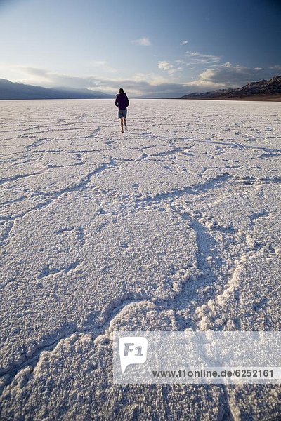 Woman walking on salt flats  Badwater Basin  at minus 282 feet the lowest point in the United States  Death Valley National Park  California  United States of America  North America