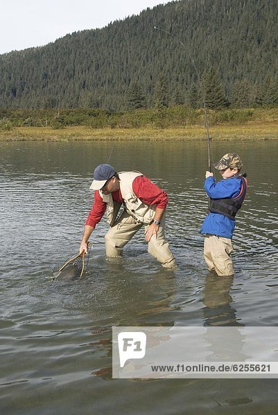 Boy catching a Silver (Coho) salmon (Oncorhynchus kisutch) with dad's help  Coghill Lake  Alaska  United States of America  North America