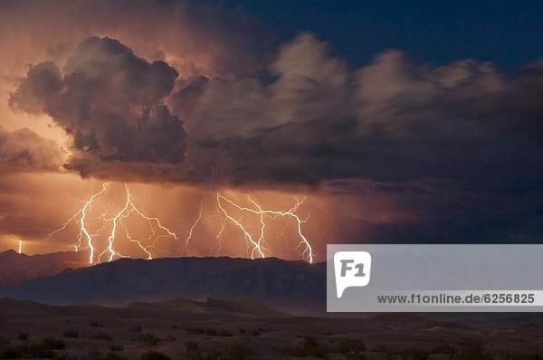 Electrical storm with forked lightning over the Grapevine mountains of the Amargosa Range  Mesquite Flats Sand dunes in the valley  Stovepipe Wells  Death Valley National Park  California  United States of America  North America