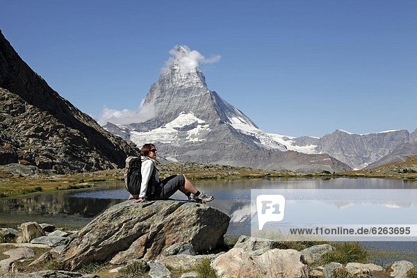 Hiker resting at Riffelsee with the Matterhorn behind  Zermatt  Valais  Swiss Alps  Switzerland  Europe