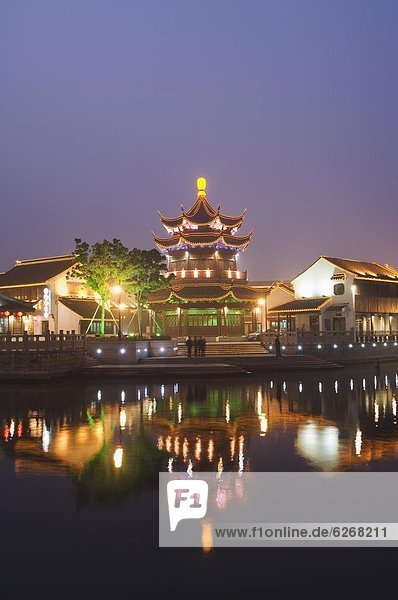 Traditio0l old riverside houses and pagoda illumi0ted at night in Shantang water town  Suzhou  Jiangsu Province  Chi0  Asia