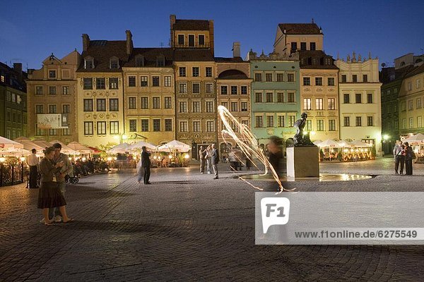 Street performers in front of houses  restaurants and cafes at dusk  Old Town Square (Rynek Stare Miasto)  UNESCO World Heritage Site  Warsaw  Poland  Europe