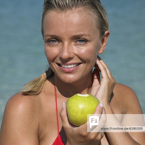 Woman on beach holding apple