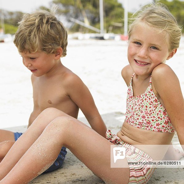 Boy and girl (6-8) sitting on beach