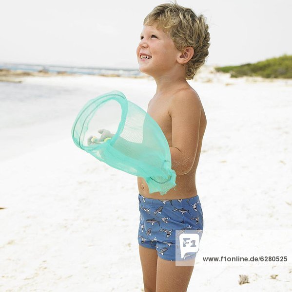 Boy (6-8) on beach with fishing pole