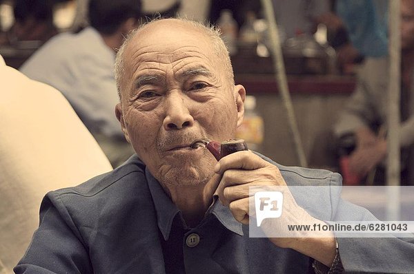 Portrait of a Chinese man smoking pipe  Yangshuo  Guangxi Province  China  Asia